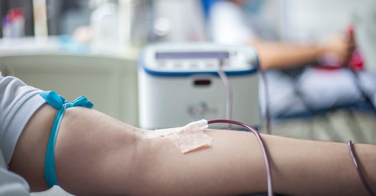 A detailed close-up of an arm during the blood donation process in a medical setting.