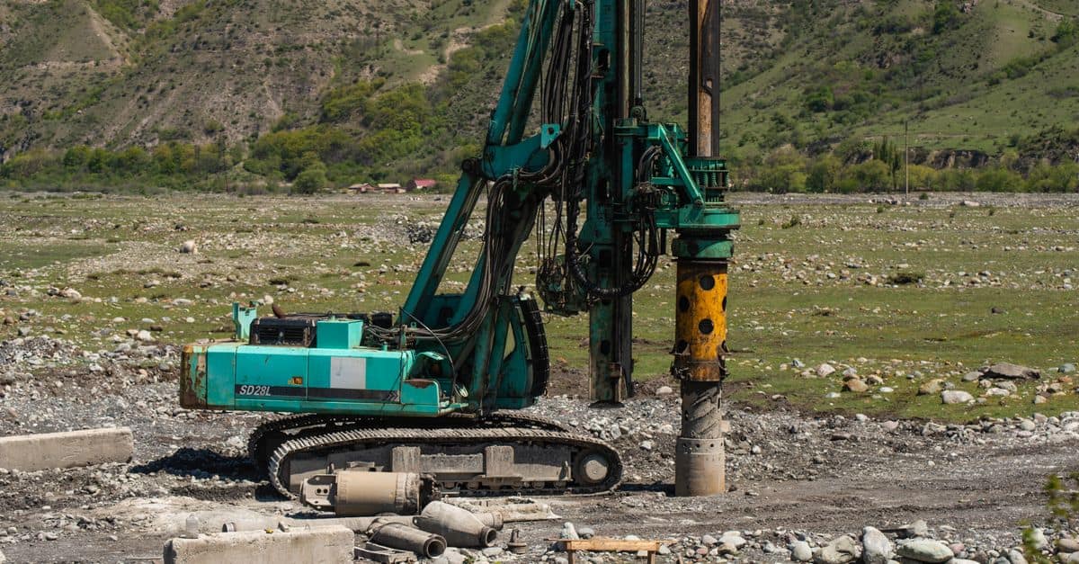 A heavy drilling machine in use on a rugged outdoor construction site.