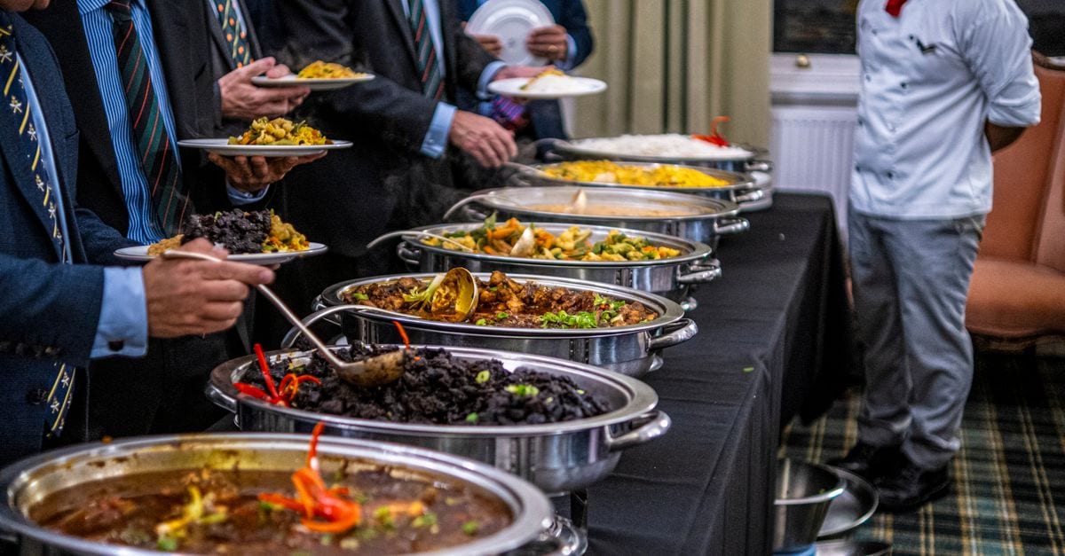 Business professionals in suits enjoy a diverse buffet lunch selection at a formal event.