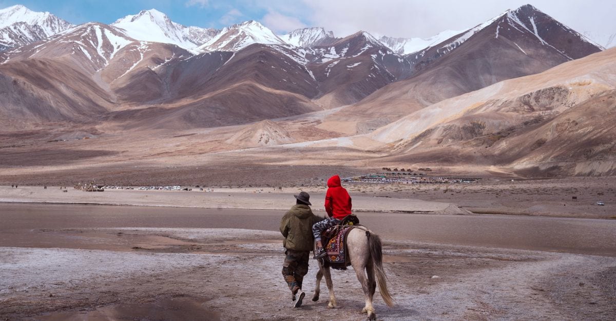 A person and child riding a horse in the breathtaking mountains of Ladakh, India.