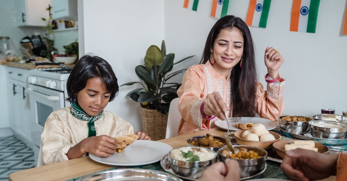 Mother and son enjoying a traditional Indian meal together at home, embracing cultural heritage.