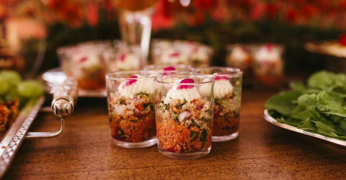 A vibrant display of gourmet appetizers in cups at a wedding reception.