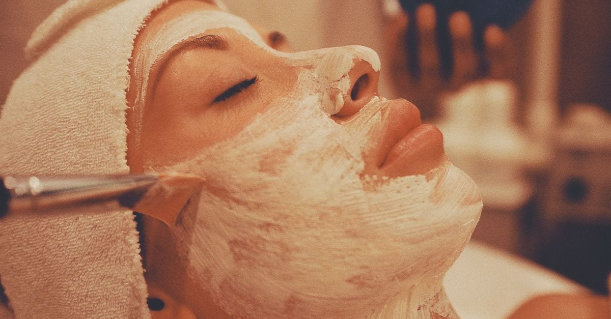 A calming spa facial treatment with a woman receiving a luxurious face mask application.