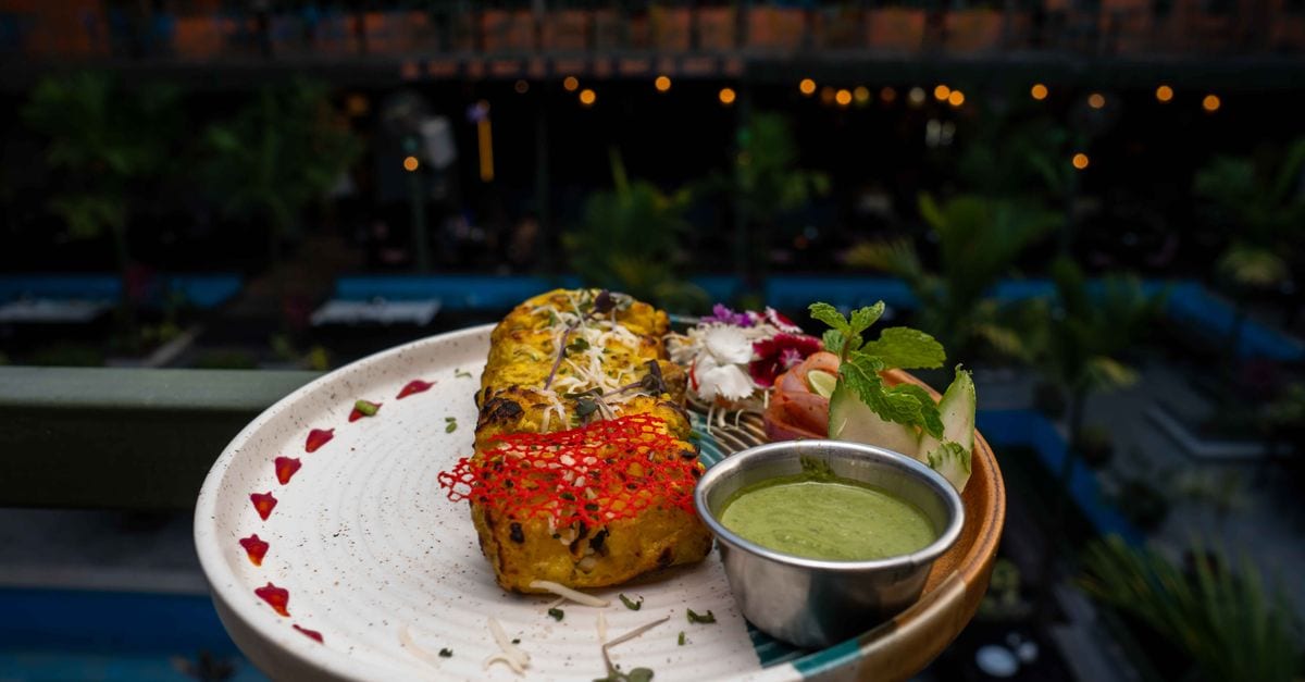 Exquisite Indian food with vibrant garnishing served on a terrace with blurred cityscape background.