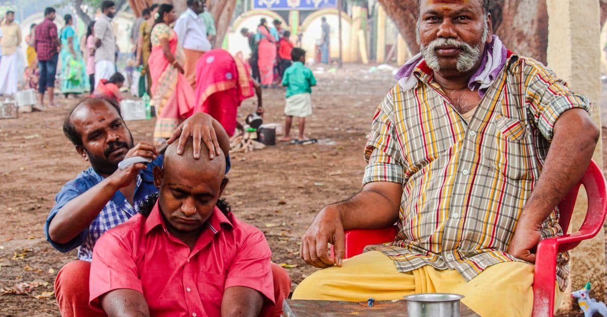 A bustling outdoor barber scene in Cumbum, India, showcasing local traditions and culture.