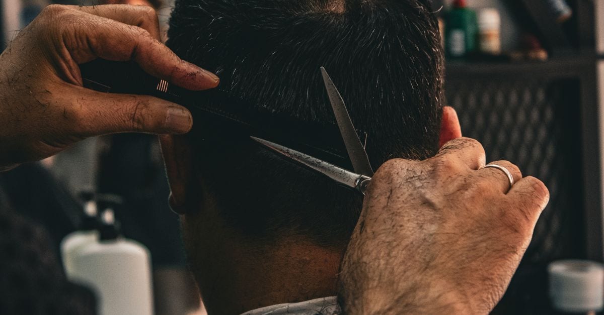 Close-up of a barber expertly cutting a client's hair, highlighting traditional grooming skills.