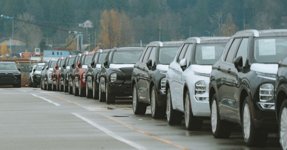 A line of new SUVs parked in an outdoor dealership lot, ready for sale.
