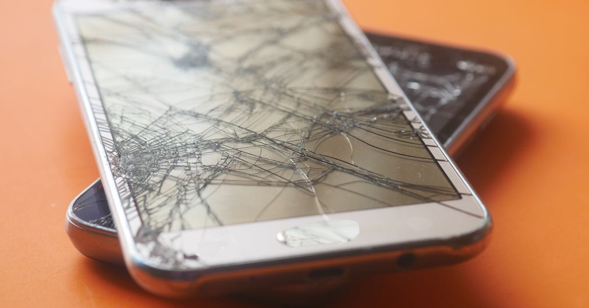 Two broken smartphone screens on an orange background, illustrating device fragility.
