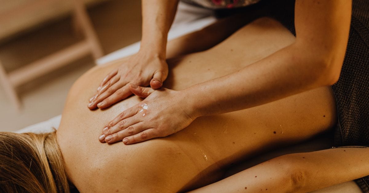 Close-up of a relaxing back massage at a spa with hands applying massage oil.